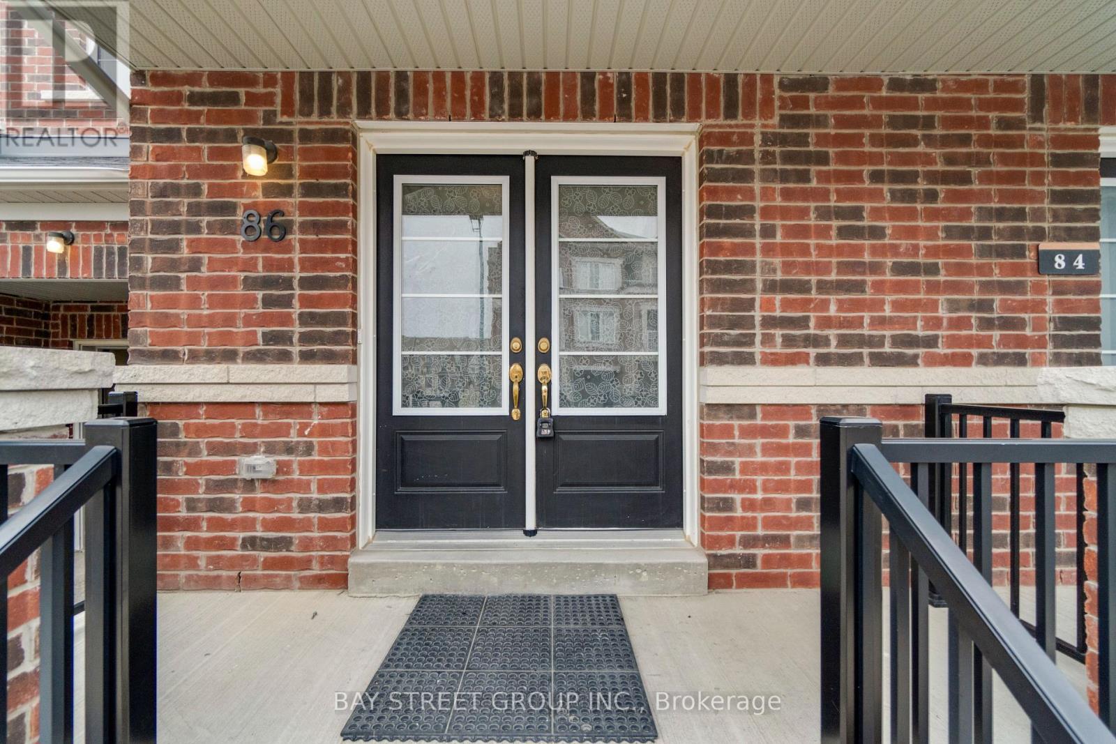 A black double door with a glass window is set in a brick wall.