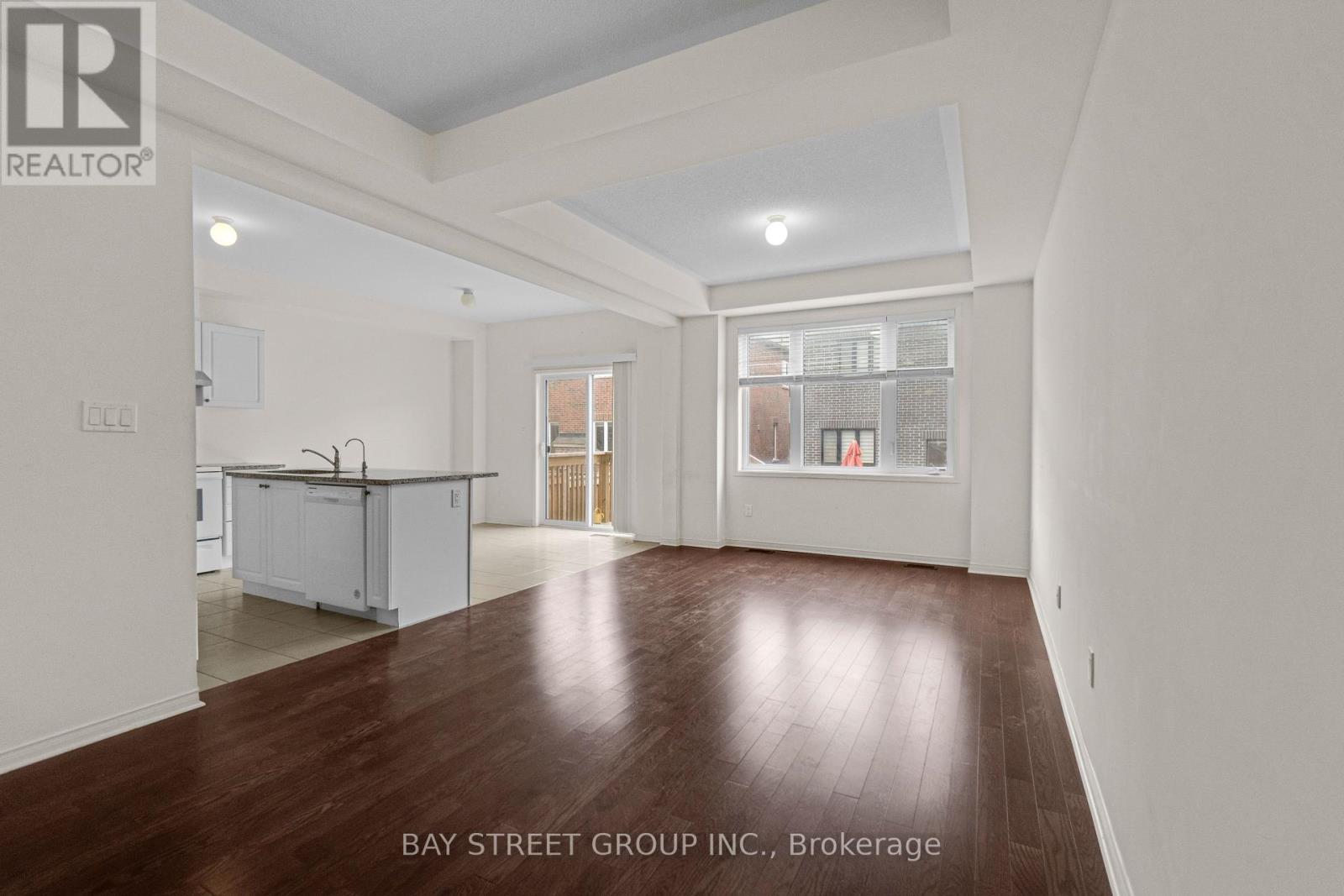A spacious room with wooden floors and white walls, part of a property brokerage by Bay Street Group Inc.
