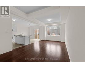 A spacious room with wooden floors and white walls, part of a property brokerage by Bay Street Group Inc.