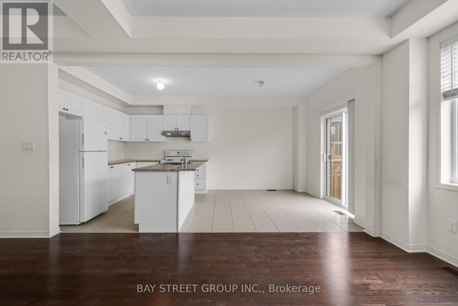 A spacious kitchen with white cabinets and a wooden floor.