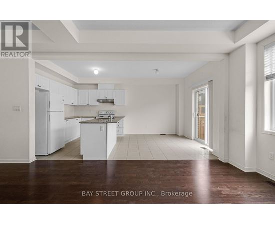 A spacious kitchen with white cabinets and a wooden floor.