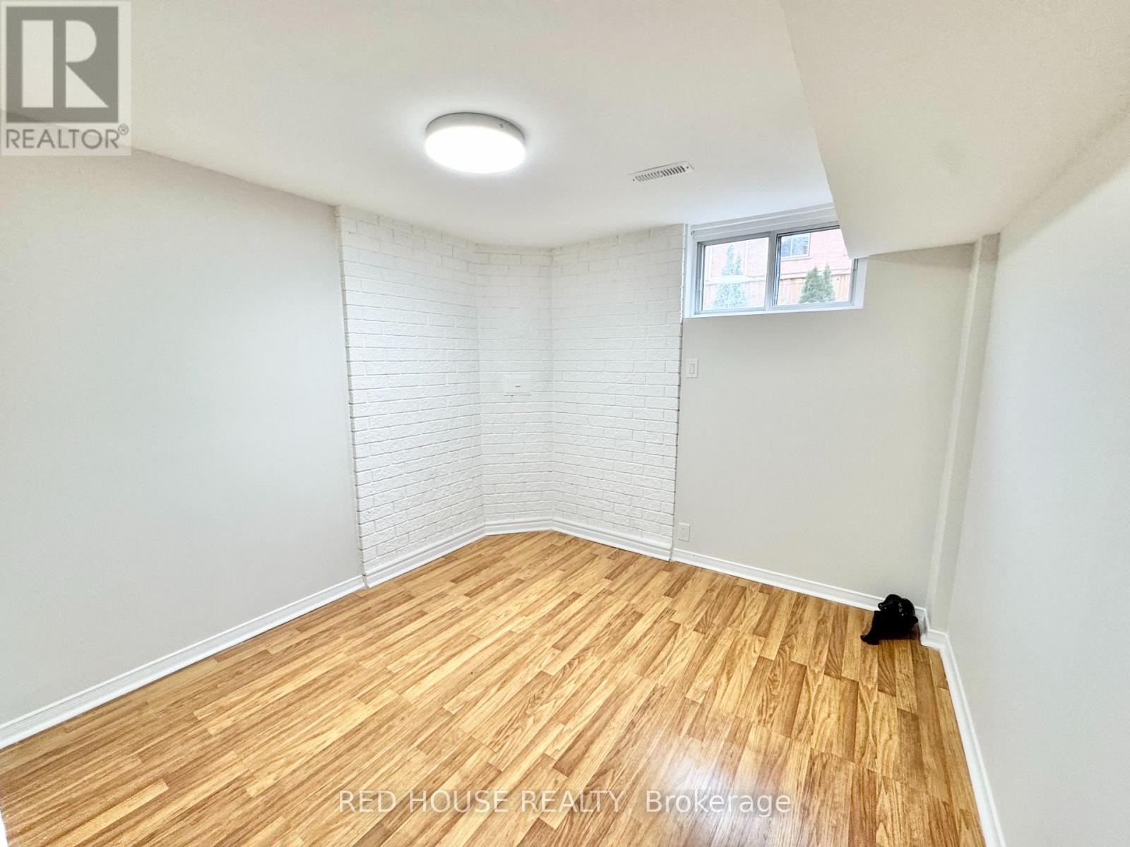 A room with wooden flooring and a window with blinds.