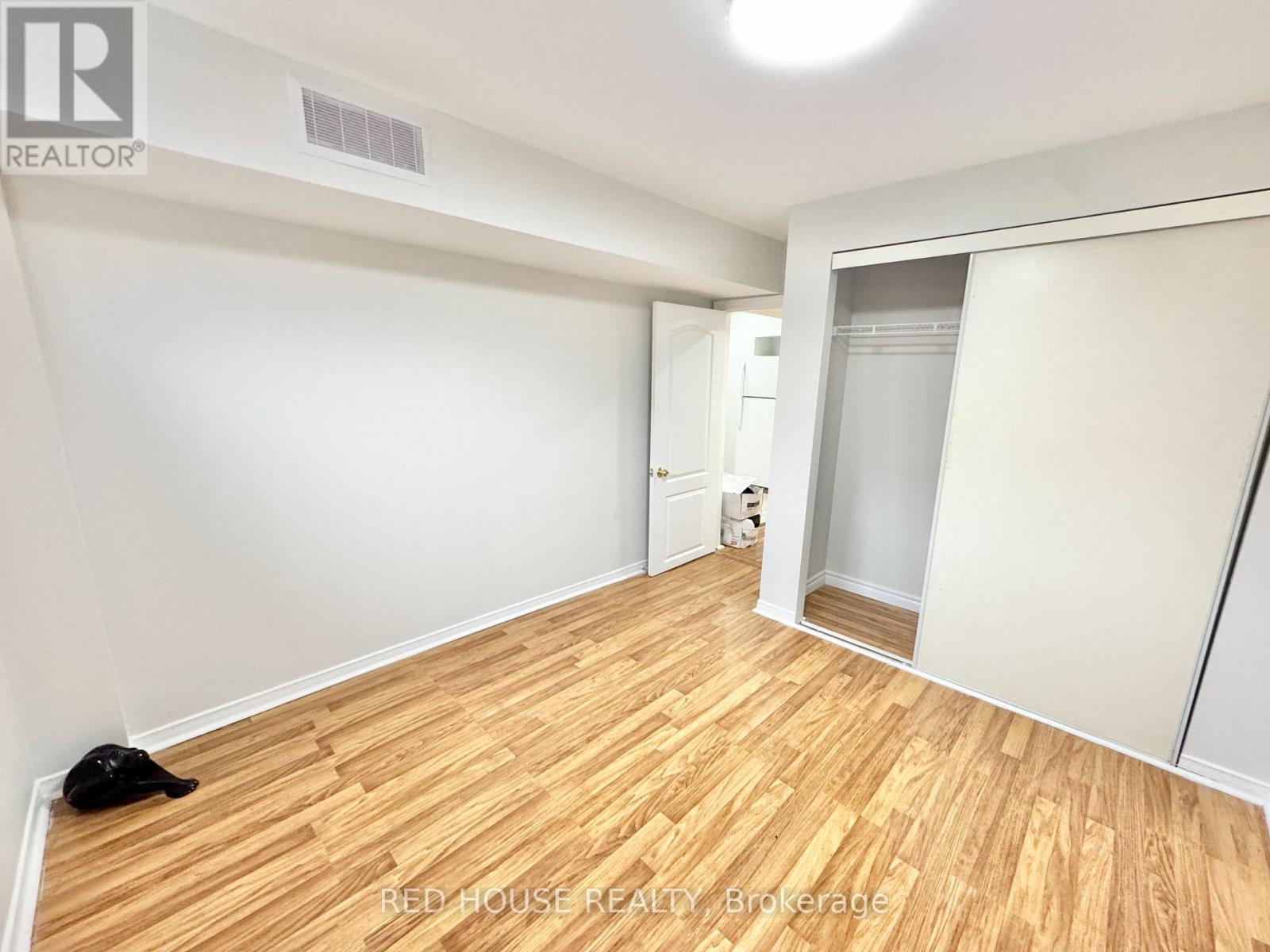 A room with wooden flooring and white walls, with a black cat lying on the floor.