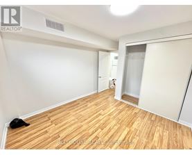 A room with wooden flooring and white walls, with a black cat lying on the floor.