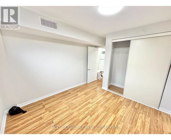 A room with wooden flooring and white walls, with a black cat lying on the floor.