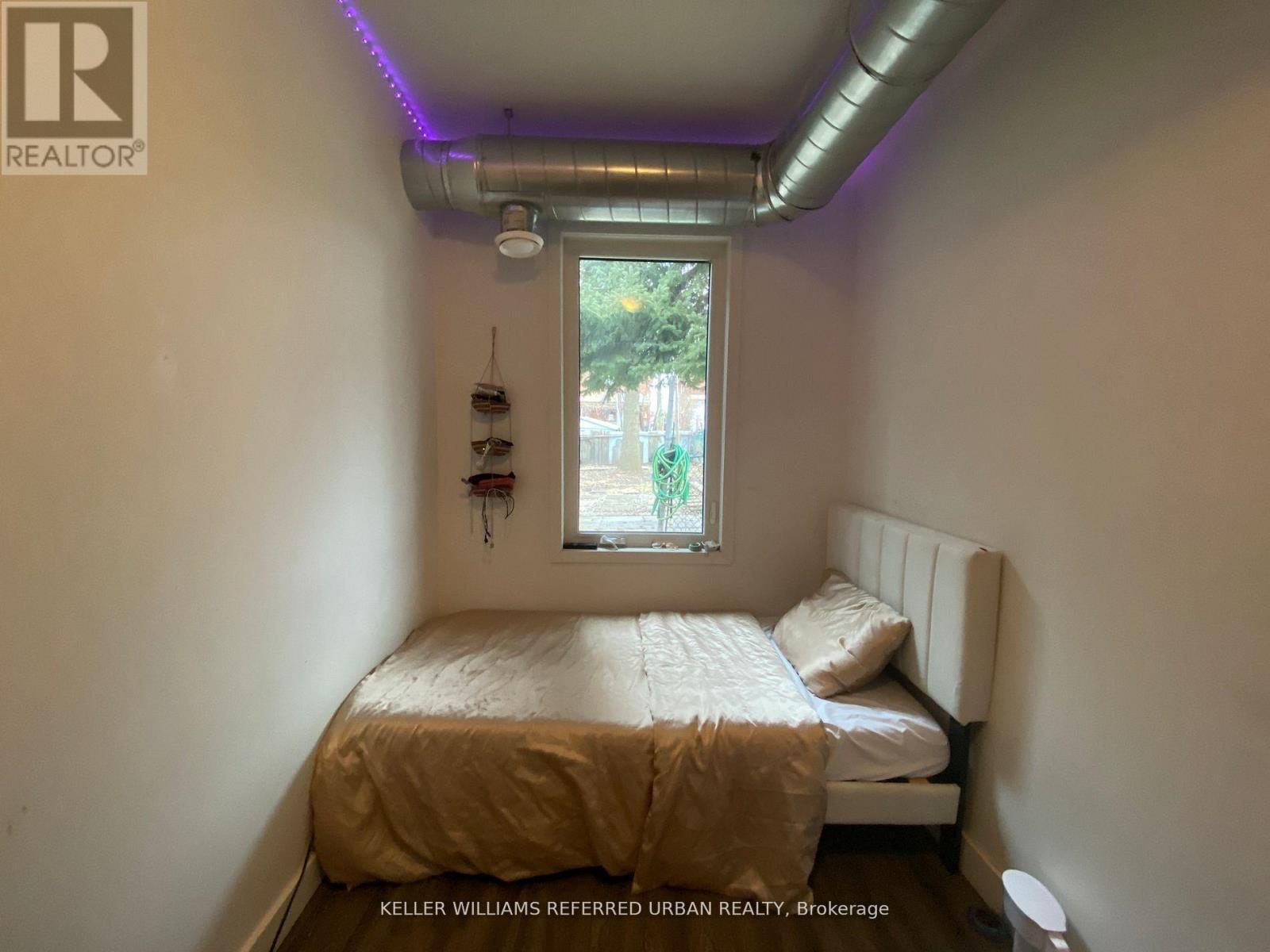 A bedroom with a bed, a window, and a wall-mounted shelf.