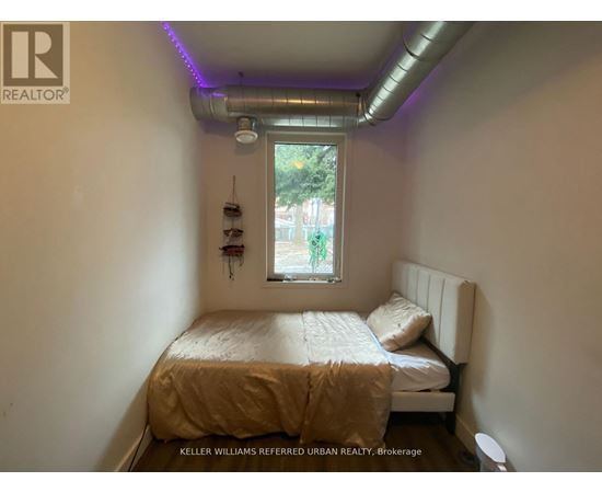 A bedroom with a bed, a window, and a wall-mounted shelf.
