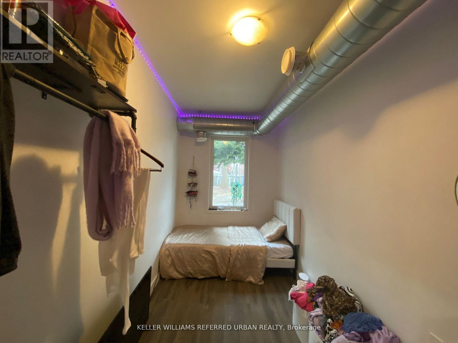 A small bedroom with a bed, a window, and a clothing rack.