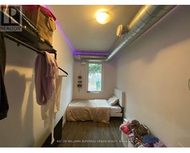 A small bedroom with a bed, a window, and a clothing rack.