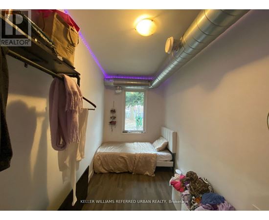 A small bedroom with a bed, a window, and a clothing rack.