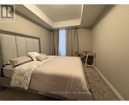 A bedroom with a large bed and a window with curtains.