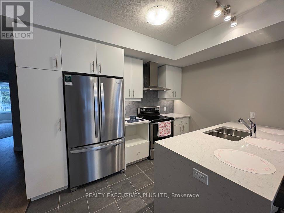 A modern kitchen with a stainless steel refrigerator and a white countertop.