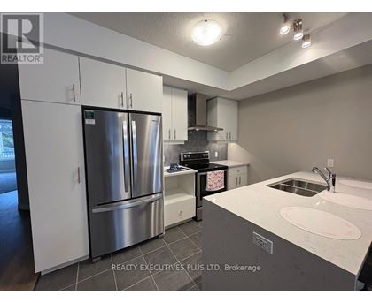 A modern kitchen with a stainless steel refrigerator and a white countertop.