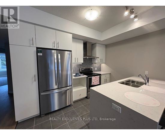 A modern kitchen with a stainless steel refrigerator and a white countertop.