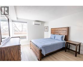 A bedroom with a bed, nightstand, and window.