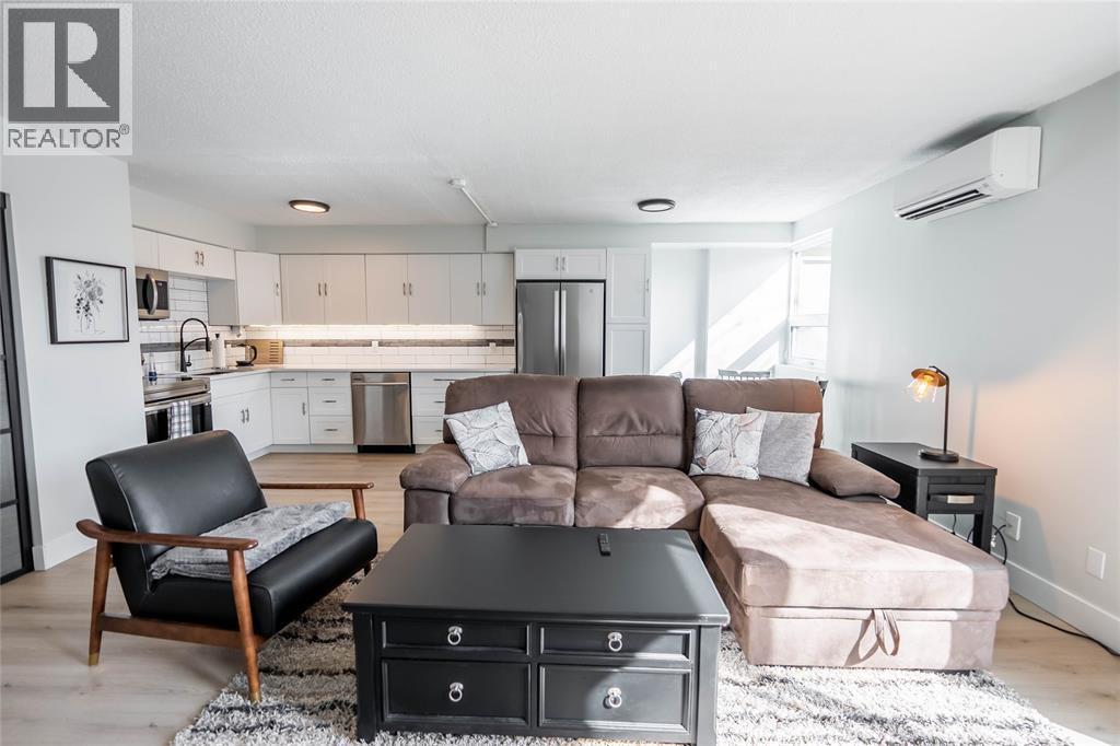 A living room with a brown couch and a black chair.