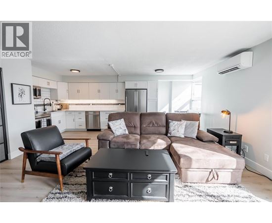 A living room with a brown couch and a black chair.