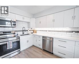 A modern kitchen with white cabinets and a stainless steel dishwasher.