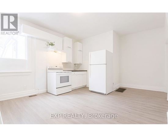 A white kitchen with EXP REALTY, Brokerage written on the floor.