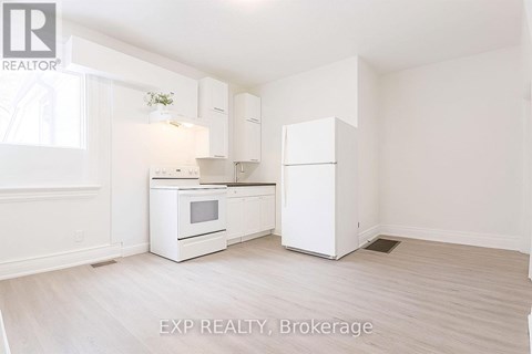 A white kitchen with EXP REALTY, Brokerage written on the floor.