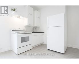 A white kitchen with a refrigerator, oven, and sink.