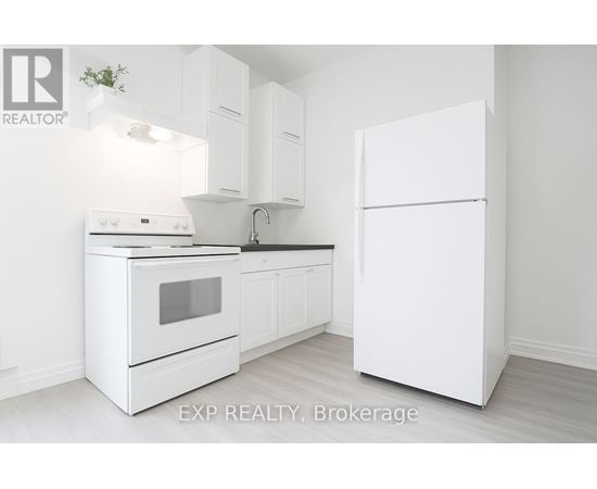 A white kitchen with a refrigerator, oven, and sink.