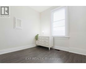 A white dresser with a mirror and a potted plant sits in a room with a window.