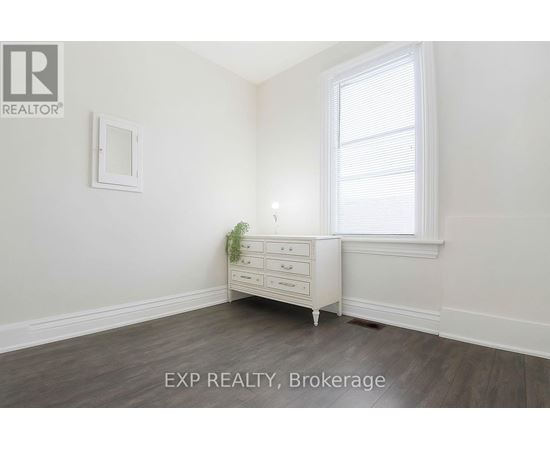 A white dresser with a mirror and a potted plant sits in a room with a window.