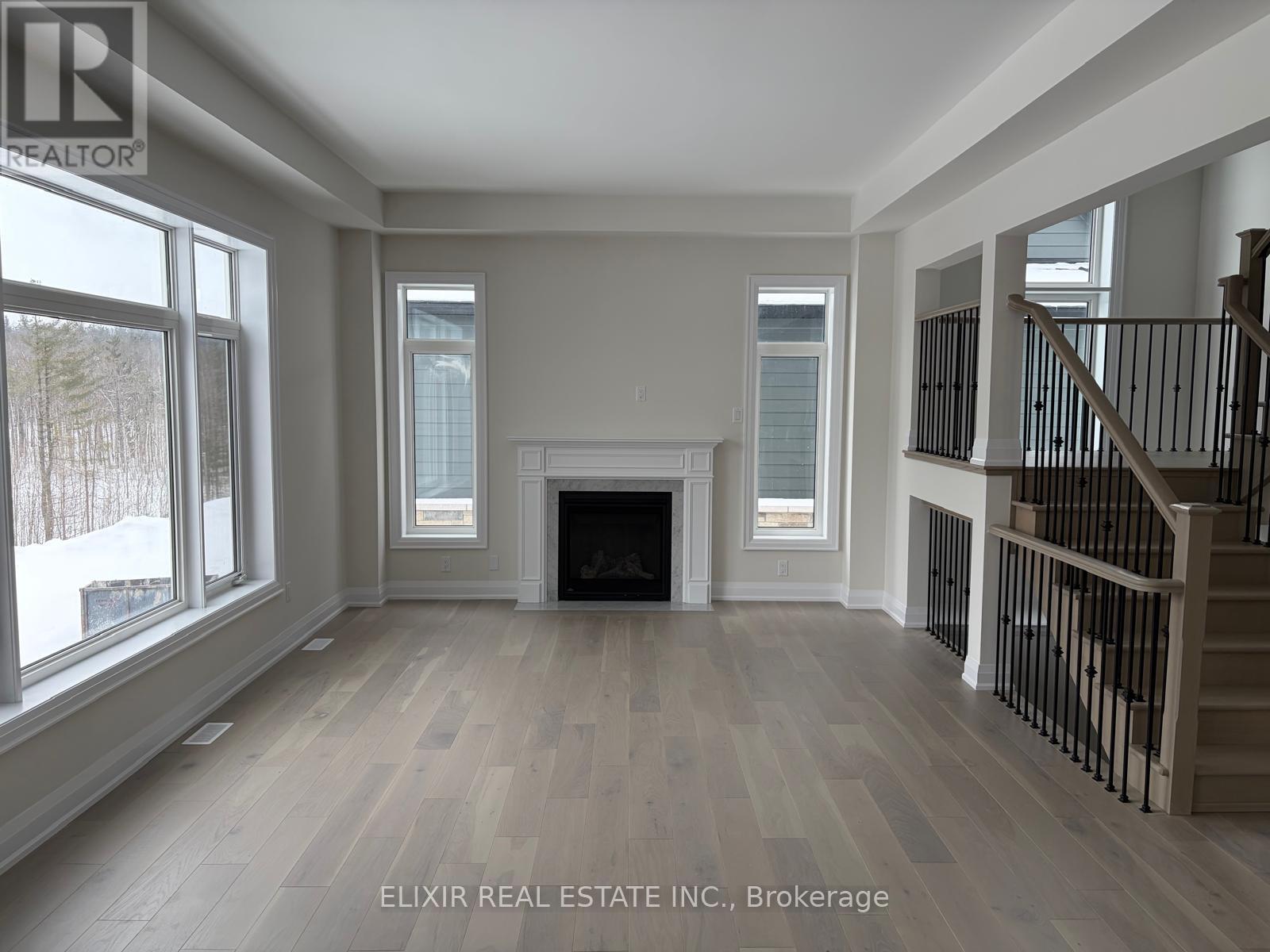 A spacious living room with a fireplace and a staircase.