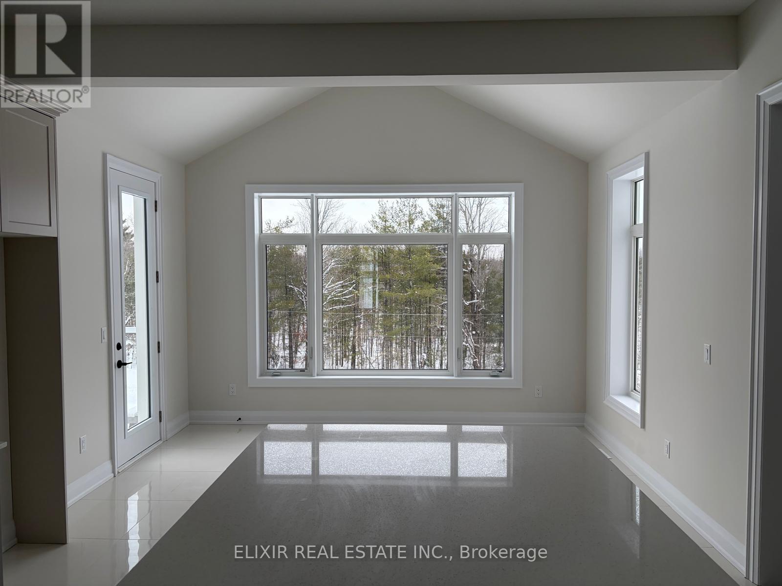 A spacious room with a large window overlooking a snowy landscape.