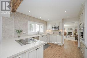A modern kitchen with white cabinets and a wooden floor.