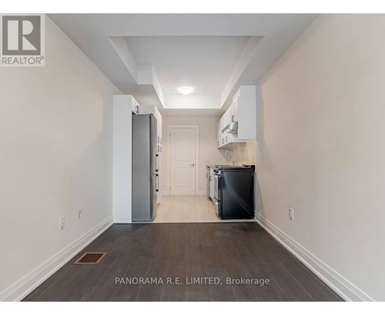 A spacious hallway with a refrigerator and a cabinet on the wall.