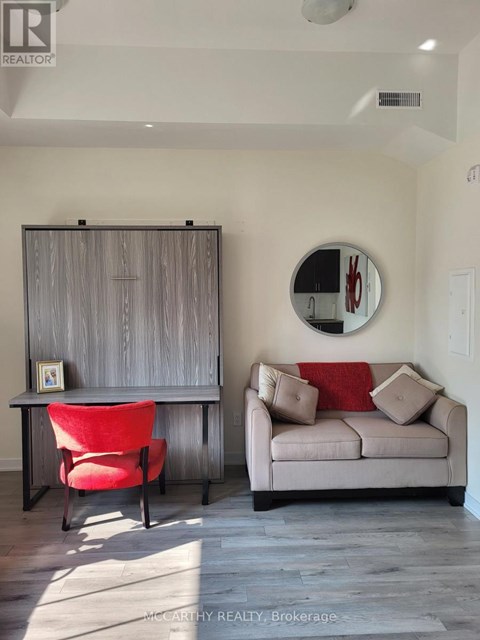 A living room with a red chair and a grey couch.