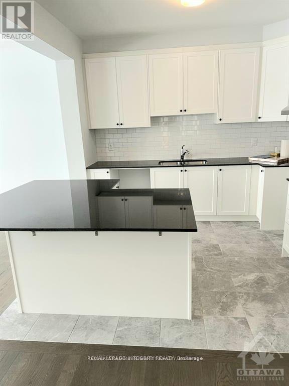 A kitchen with white cabinets and a black countertop.