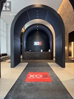 A hallway with a red carpet and a black archway with the letters XO on it.