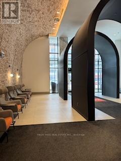 A hallway with a brick wall and a row of chairs.