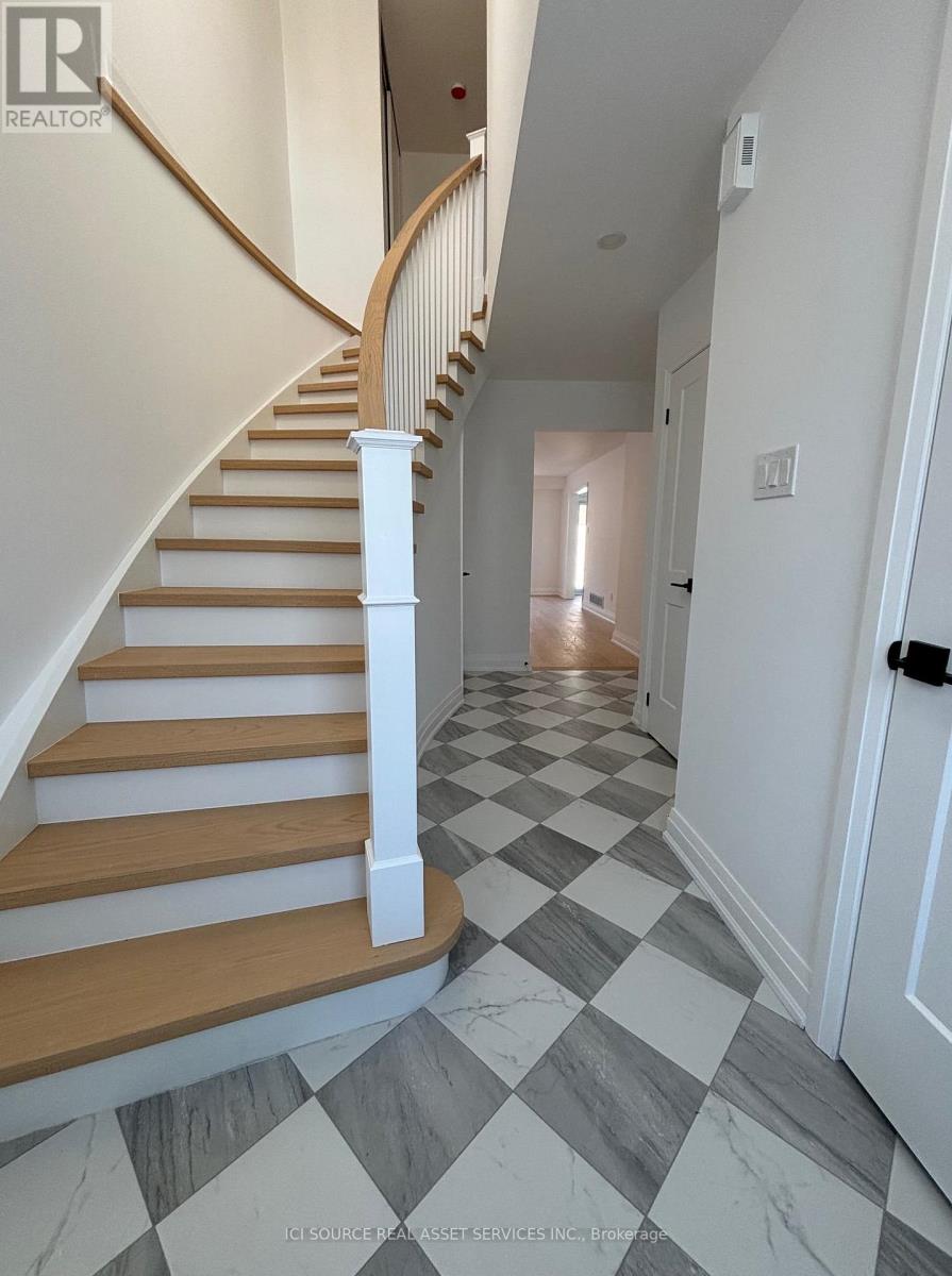 A hallway with a checkered floor and a staircase.