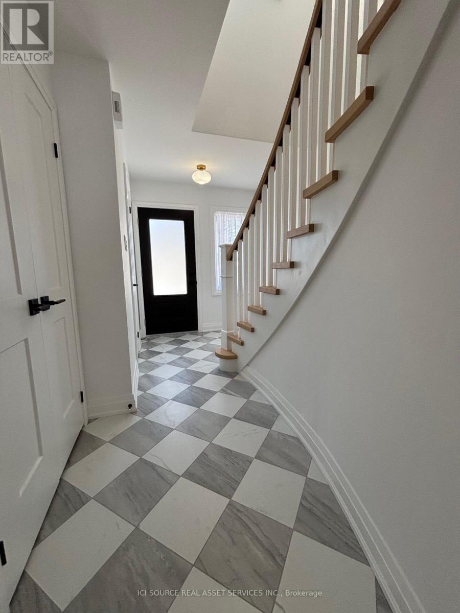 A hallway with a checkered floor and a staircase.