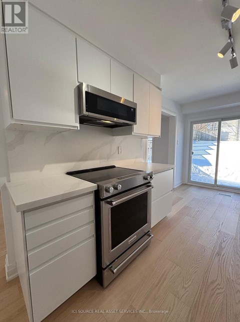 A modern kitchen with white cabinets and a black stove top oven.