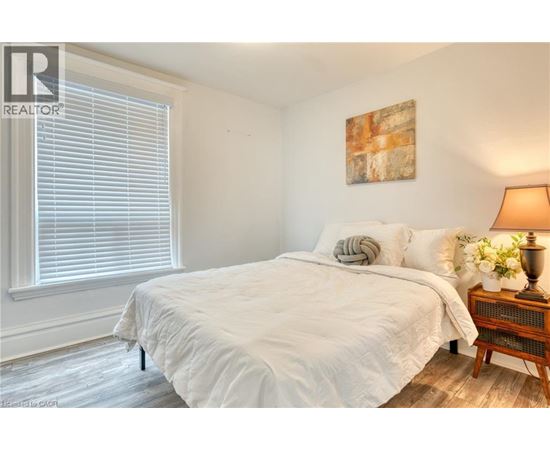 A bedroom with a large bed and a wooden nightstand.