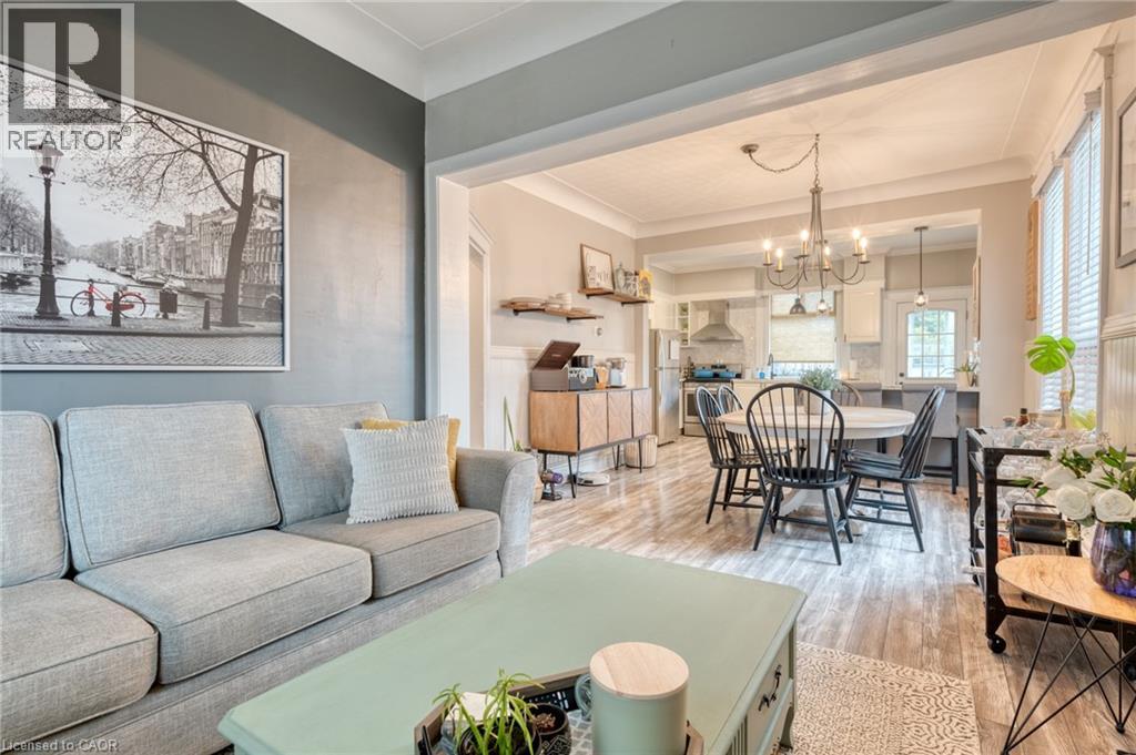 A living room with a grey couch and a dining area with a table and chairs.