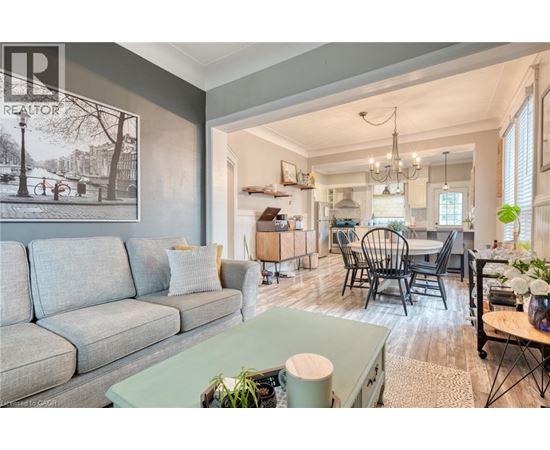 A living room with a grey couch and a dining area with a table and chairs.