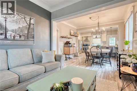 A living room with a grey couch and a dining area with a table and chairs.