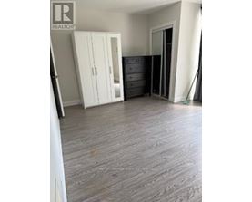 A bedroom with a wooden floor and a white wardrobe.