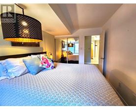 A bedroom with a large bed and a hanging light fixture.
