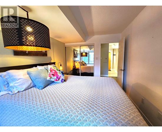 A bedroom with a large bed and a hanging light fixture.