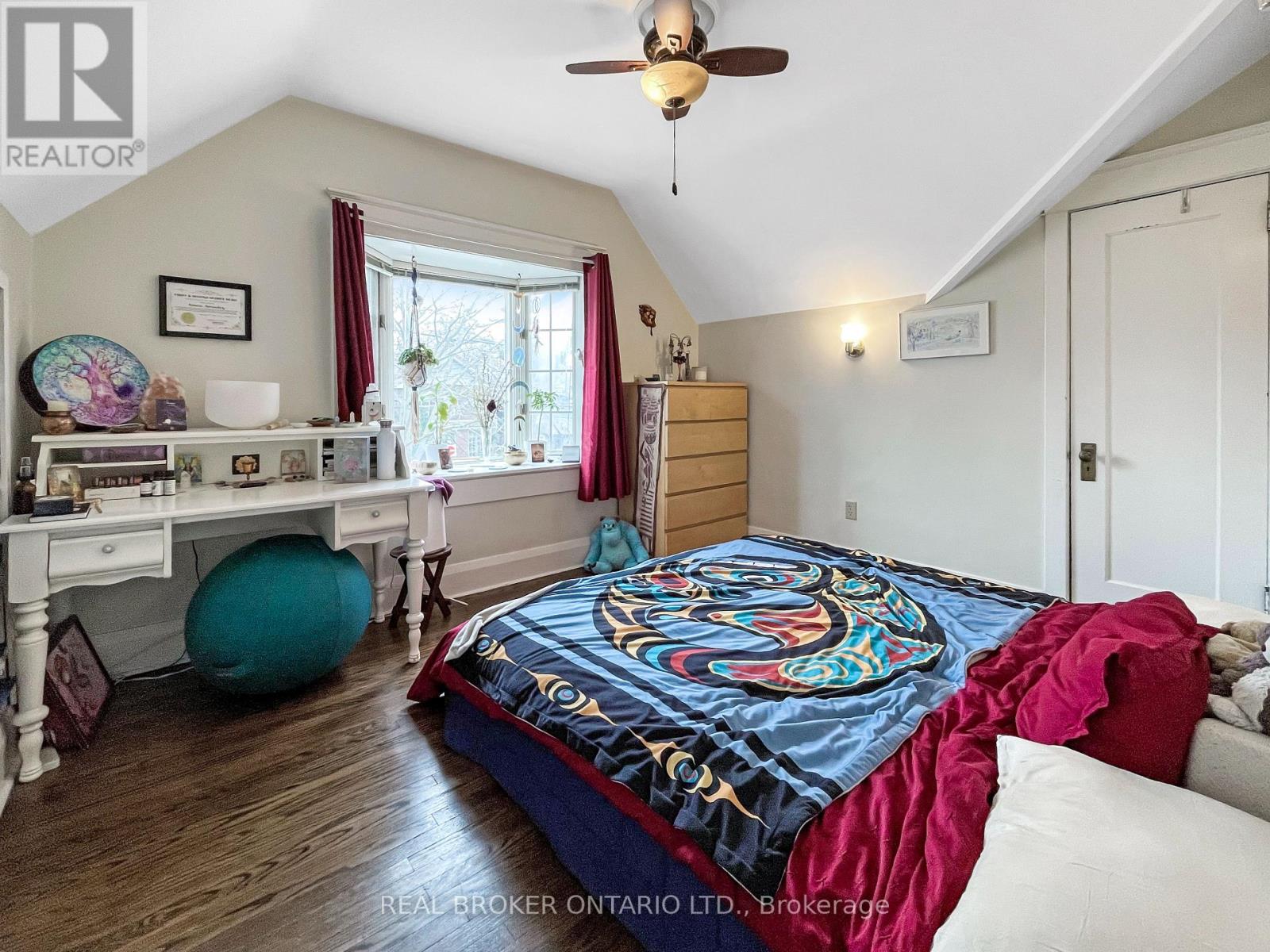 A bedroom with a bed in the center and a desk to the left.