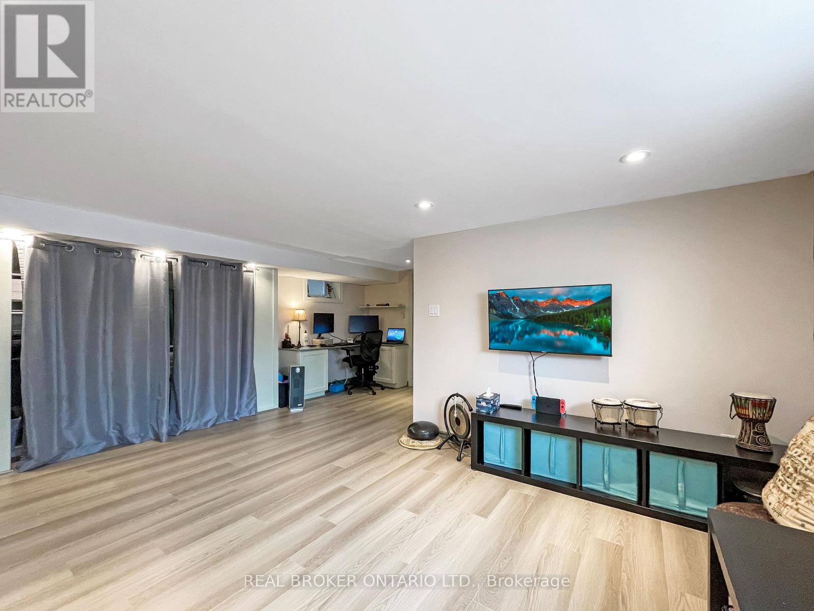 A spacious room with a desk, chairs, and a painting on the wall.
