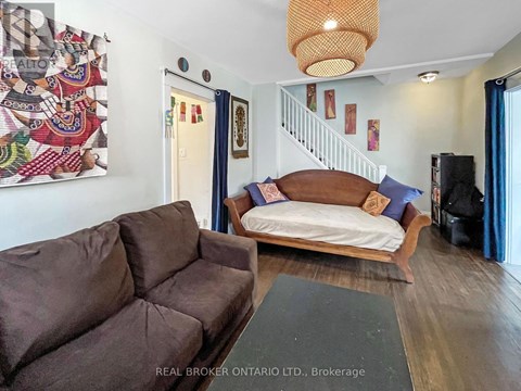 A living room with a brown couch and a white bed.