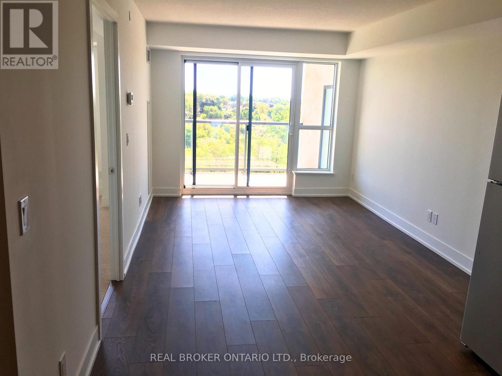 A room with wooden flooring and a sliding glass door leading to a balcony.